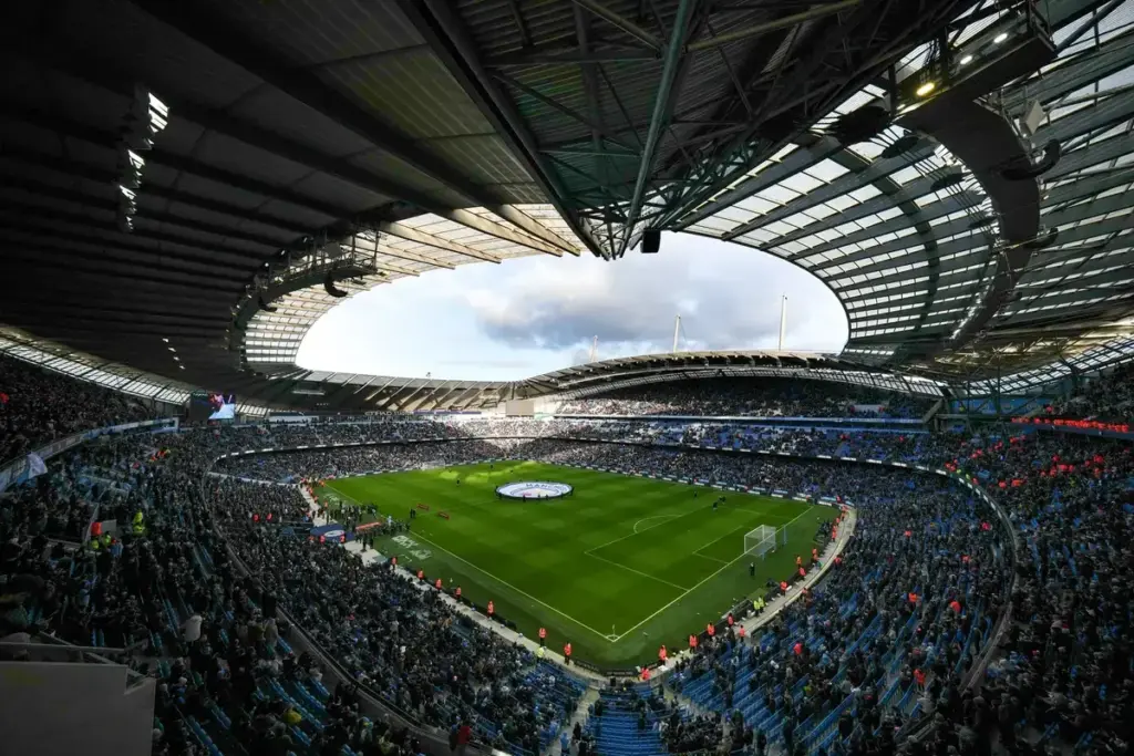Man City Premier League legal action: An interior wide view of the Etihad Stadium with a circular Manchester City crest banner on the pitch.