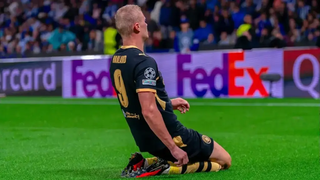 Erling Haaland celebrating on his knees in a Manchester City kit